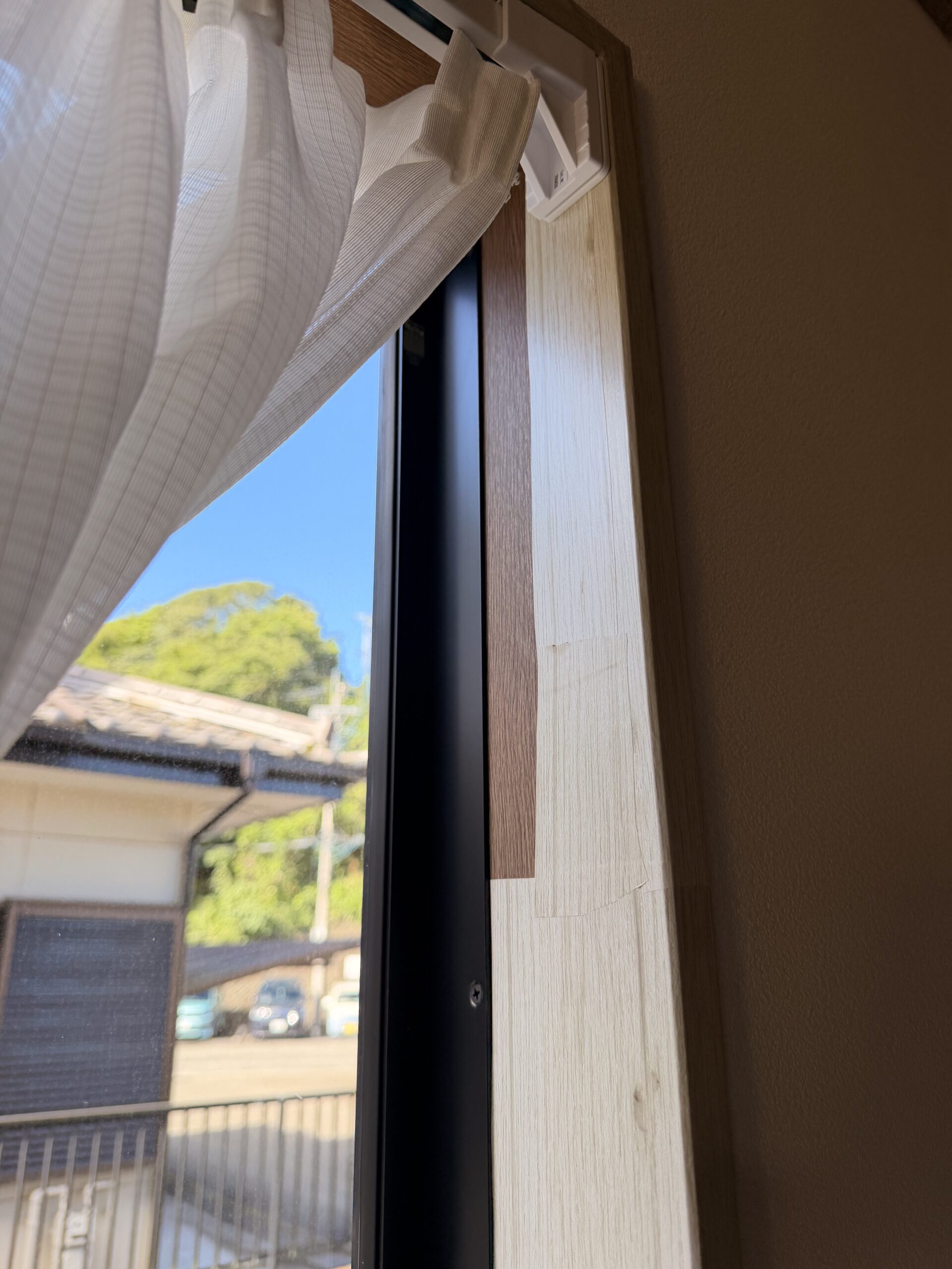 100均の木目調シートがつぎはぎになった補修前の窓枠